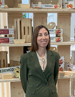 Retrato profesional de Ángela López Martín, del Departamento de Administración, con fondo de estantería de cajas de madera.