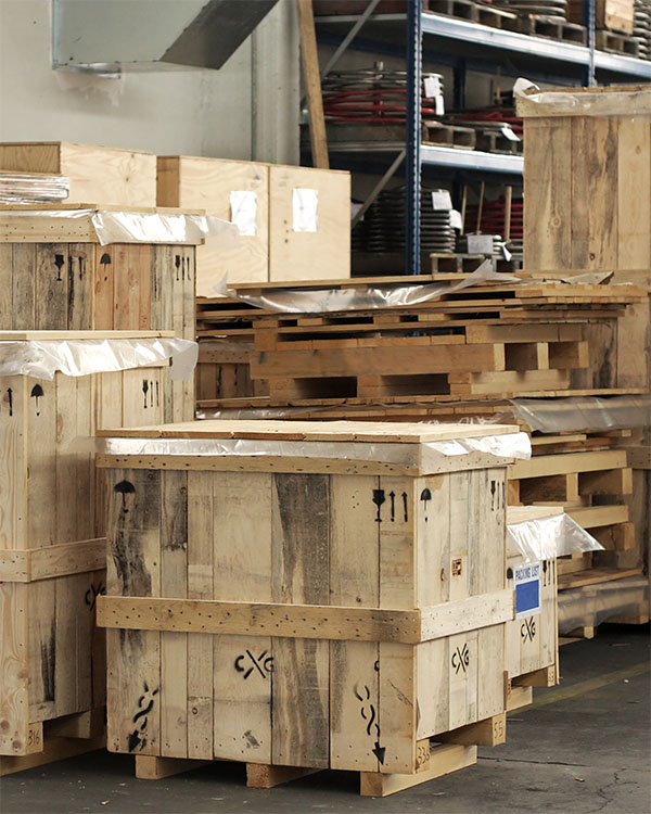 Cajas de madera de embalaje industrial apiladas en un almacén logístico con pictogramas de seguridad internacionales visibles